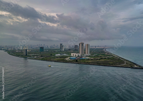 Aerial view of the modern skyscrapers of Eko Atlantic City and the coastline of Tarkwa Bay Beach under a cloudy sky in Lagos, Lagos, Nigeria.