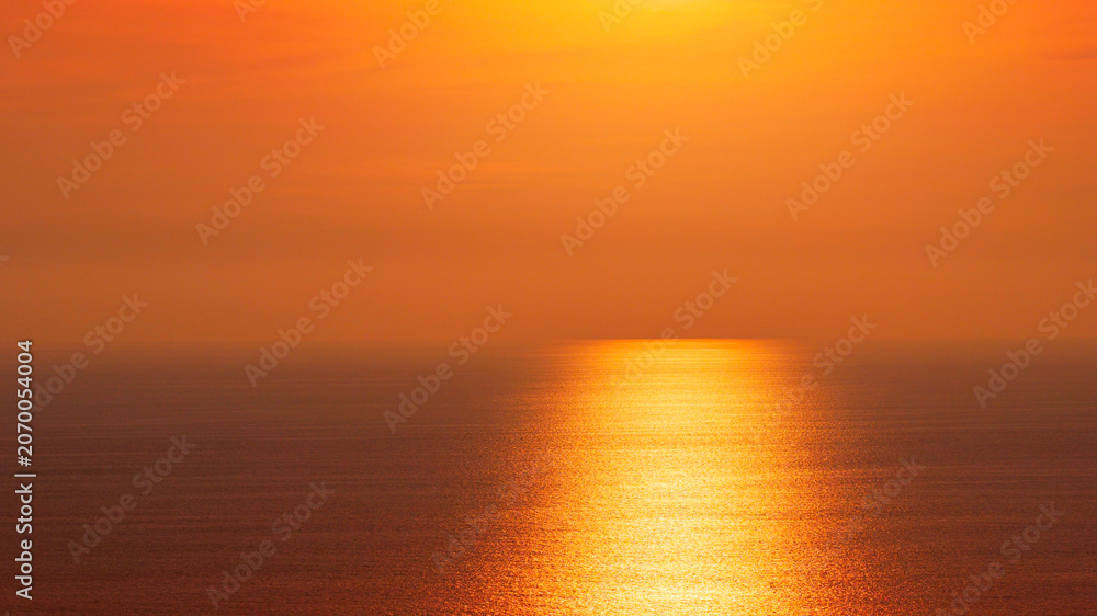 Fototapeta premium The beautiful golden sunset over the calm ocean horizon with sun reflection on water surface background