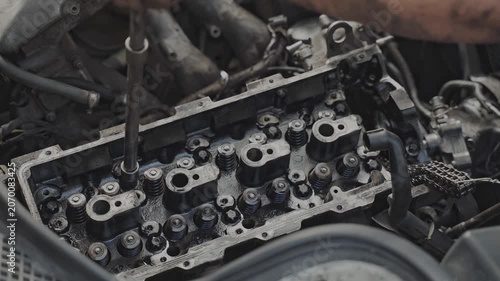 Close-up of a mechanic's hand working on the engine head of a car in an auto repair shop. Professional maintenance.