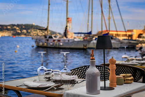 Tableau sur toile A table at an outdoor restaurant with a view of boats in the marina on the Medit