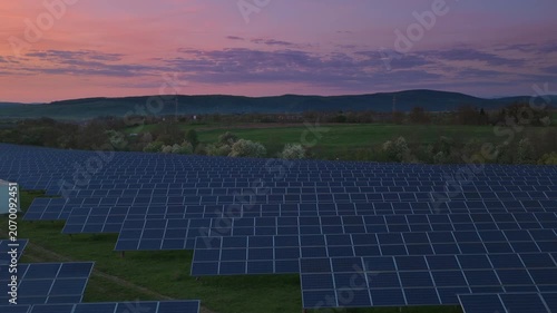 Solar farm and battery storage at twilight, low aerial lateral tracking shot