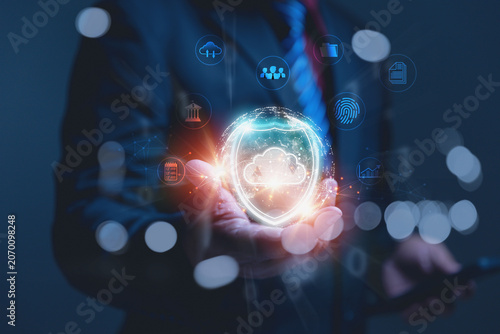 Businessman holding a glowing cloud security shield network icon.