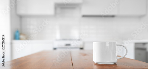 White ceramic mug on a wooden kitchen table right side