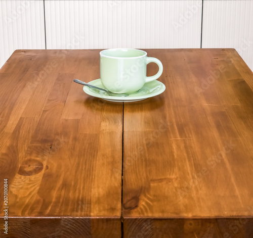 Pastel green coffee cup on a saucer on wooden table