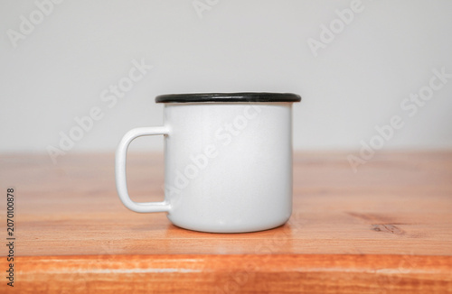 White ceramic enamel camping mug on a wooden surface