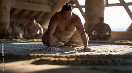 Sumo wrestlers in mawashi training at a beya stable before sunrise, slapping salt and stamping the clay dohyo in shiko drills, the stable master seated cross-legged at the edge