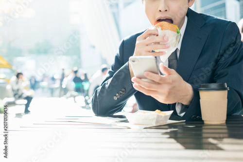 Foto ハンバーガーとスマートフォンを持つ手元