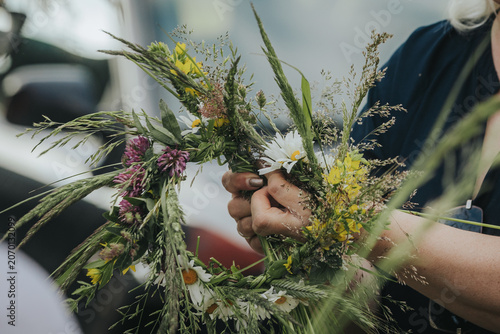 Fotografie Woman holding a handmade floral crown made of wildflowers and grasses, with vibr