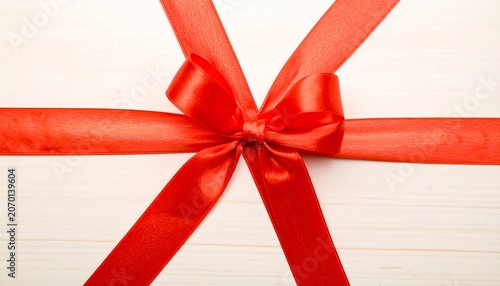 Red Ribbon Bow on Wood Surface.