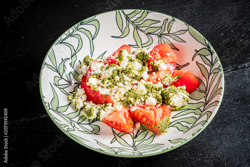 Fresh tomatoes topped with creamy cheese and vibrant green pesto for a delightful summer dish