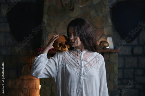 Φωτογραφία Woman gently grasping skull amidst candlelit stone setting for contemplative study