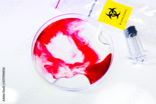 Abstract top view of Bacteria and microbes of red liquid cells in glass petri dish with biohazards icon, syringe isolated on white background. scientific research of viruses concept.