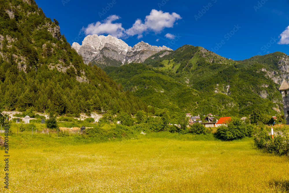Obraz premium Mountain landscape in the Albanian Alps near Theth, Albania. Theth Valbona valley trek Peaks of the Balkans scenic way. Rugged peaks rise above forested valleys and alpine meadows