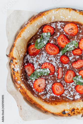 Delicious dessert pizza topped with fresh strawberries and mint leaves for a sweet treat