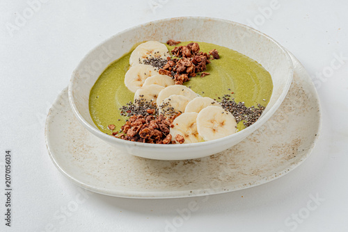 Delicious green smoothie bowl topped with fresh banana slices and crunchy granola