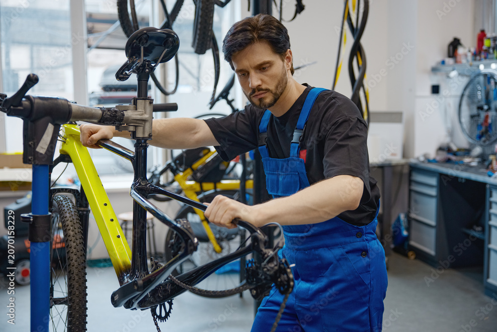 Naklejka premium Skilled worker calibrating bicycle brake cable in workshop
