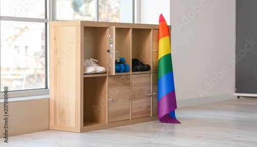 Gym Locker: An open gym locker showing athletic gear, sneakers, and a water bottle. A pride flag sticker is cleanly pasted on the inside of the locker door.
