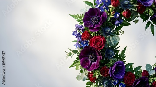 A beautiful circular floral arrangement featuring deep purple anemones, blue thistles, and red roses, set against a soft, subtly lit background