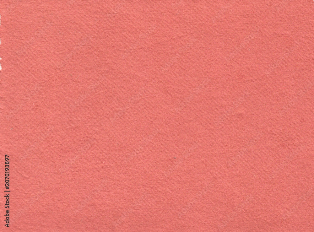 Fototapeta premium texture of handmade recycled paper in vibrant salmon pink. The solid color surface shows fine grain, elegant natural fiber patterns, and a matte appearance perfect for artistic scrapbooking.