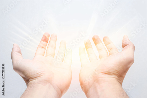 Spiritual healing and hope concept. Open human hands reaching toward a bright glowing light, symbolizing faith, healing, positive energy, inner peace, hope, gratitude, prayer, divine guidance, protect
