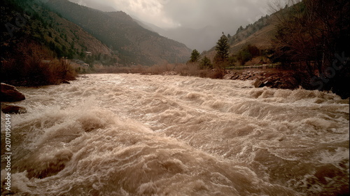 Rushing river water flows powerfully through a majestic canyon, creating a dynamic natural landscape with a cloudy sky overhead, highlighting environmental flow and nature's raw power