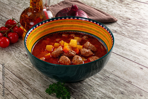 Bild auf Leinwand Hearty meatball stew with vegetables in colorful bowl on rustic wood table