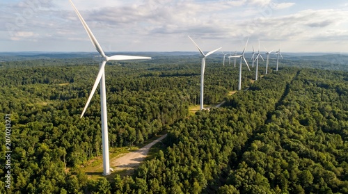 Wind turbines above lush forest landscape aerial panorama