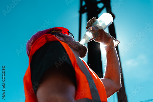 Fotografie Bauarbeiter trinkt Wasser bei strahlender Sonne