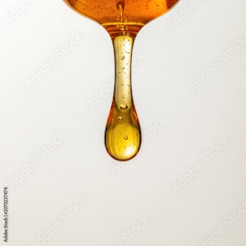 Golden Honey Droplet Dripping from Spoon Macro Shot.