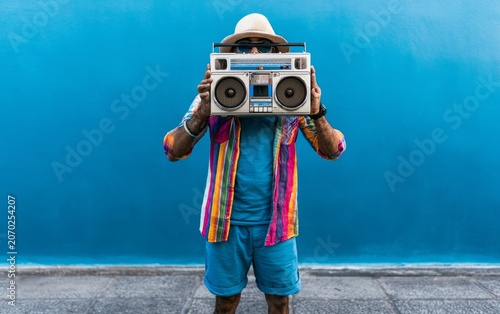 Colorful Vintage Portable Boombox Held by Stylish Individual Against Bright Blue Wall