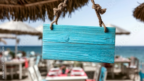 Blue Wooden Hanging Signboard at Seaside Restaurant with Tables and Sun Umbrellas in Background
