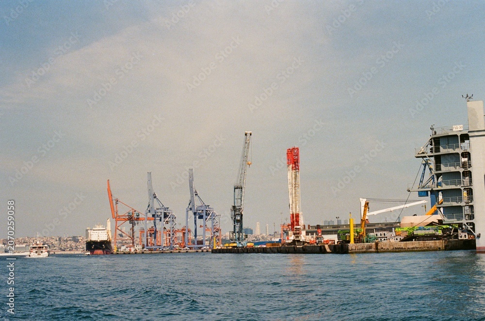 Fototapeta premium Industrial Port with Cargo Ships and Cranes on the Waterfront 