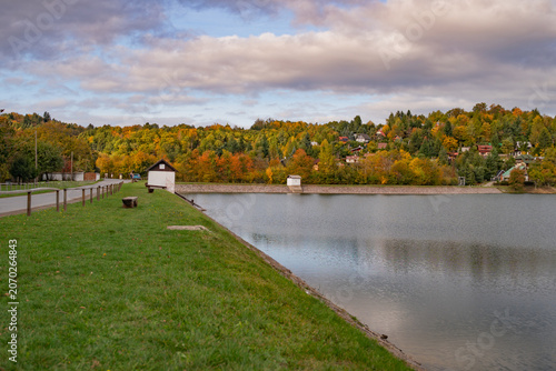 View of Velka Richnava lake with vibrant autumn foliage and grassy banks Stiavnicke Bane, Banska Bystrica Region, Slovakia.