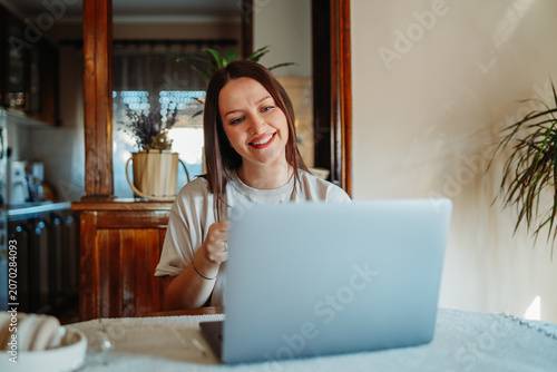 Young woman remotely working on laptop from home
