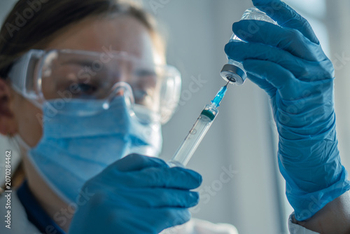 A close up image shows a medical worker drawing liquid from a vial into a syringe, emphasizing vaccination and health care. The scene highlights modern medicine and disease prevention