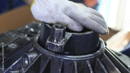 Close-up of a mechanic using a hammer and puller tool to disassemble the rear cover from an automatic transmission.