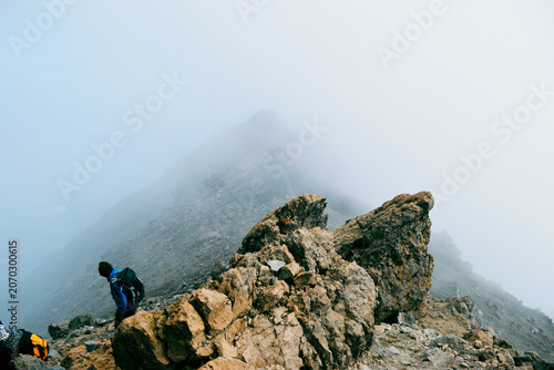 A Group of Hikers Standing on the Volcanic Rim above the clouds on a foggy day in the Alpine Desert Zone of Mount Meru, Arusha National Park, Tanzania