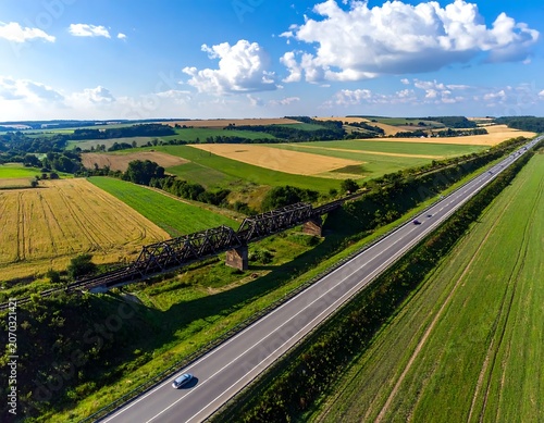Scenic Rural Highway Running Through Patchwork Farmland Under Blue Cloudy Sky