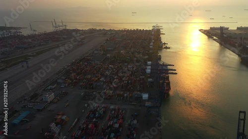 Hazy Sunset Illuminates Vast Cargo Port with Massive Containers and Industrial Cranes Amidst Dynamic Shipping Operations at Modern Port Infrastructure, showcasing global trade activity.