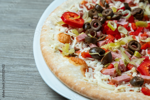 Pizza on plate. Freshly sliced pizza displayed on clean surface. Single slice of pizza with toppings on plain white dish