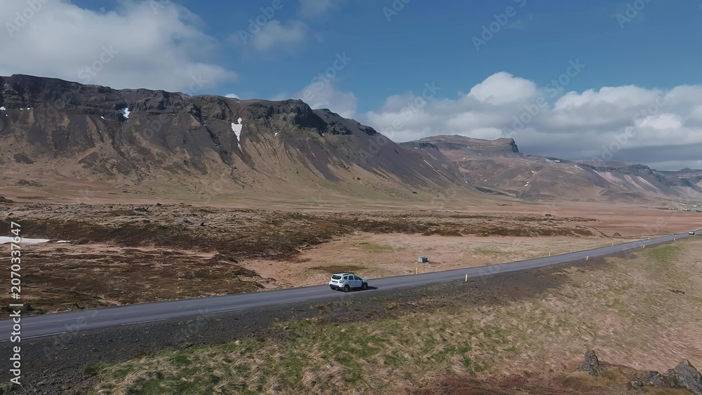 Fototapeta premium White car driving on a sandy desert road under blue sky
