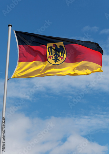 Wehende Deutschlandfahne am Flaggenmast mit Bundeswappen (Bundesadler) in der Mitte, Hochformat