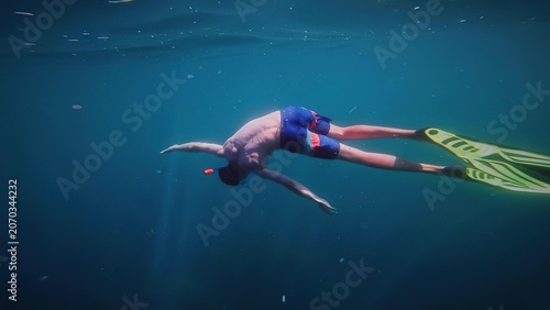 Foto Man snorkeling underwater with fins in clear blue water