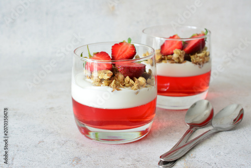 Strawberry dessert with jelly, yogurt and Granola in Glasses with spoons