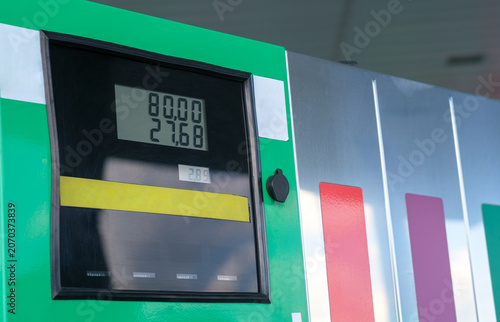 Fuel pump displays exact price per liter. Green and silver station design is modern. Yellow stripe separates price and quantity.