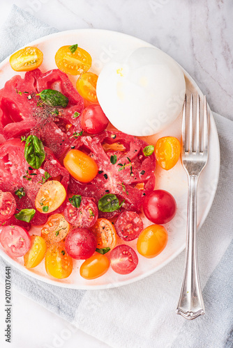 Burrata cheese with organic  yellow and red tomatoes, basilic and herbs. Summer Italian lunch