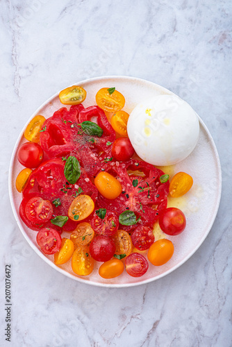 Burrata cheese with organic  yellow and red tomatoes, basilic and herbs. Summer Italian lunch
