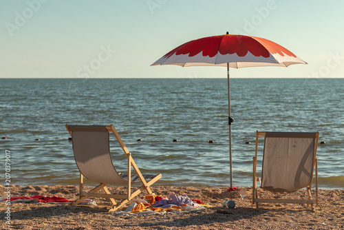 Cuadro en lienzo Two wooden sun loungers on a sandy beach overlooking the sea