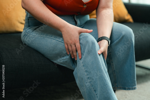 Fotografie Plus Size Woman Suffering From Knee Pain While Sitting at Home