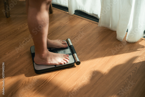 Plus Size Woman Stepping on Weighing Scale During Weight Management Journey
